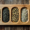 Assorted Loose Leaf Teas on a Bamboo Tray Top-down view of different types of loose leaf tea--green, black, oolong, and flower--neatly displayed on a bamboo tea tray.