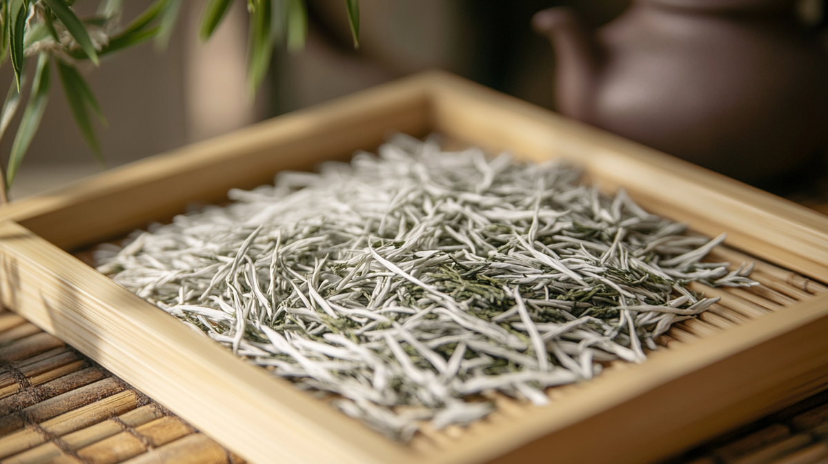 Close-up of Silver Needle white tea leaves, covered in silvery white hairs, arranged neatly on a bamboo tray.