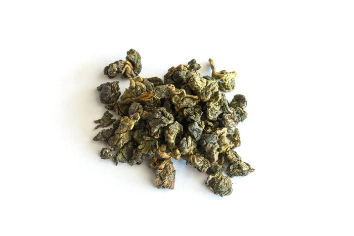 A close-up of Milky Oolong tea leaves, tightly rolled into small, greenish-brown pearls, showcasing their natural texture and color on a white background.