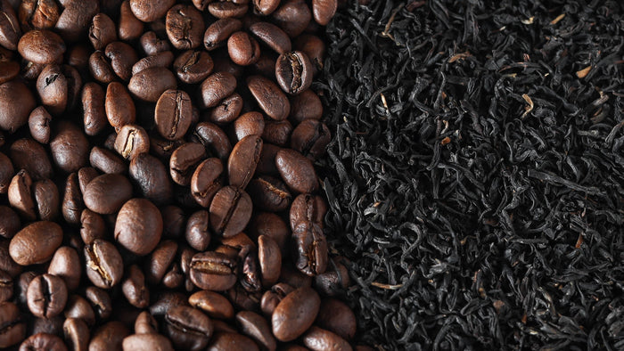 A close-up comparison of roasted coffee beans and dried black tea leaves, highlighting their differences in texture and caffeine content.