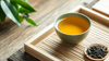 A warm cup of green tea with fresh tea leaves on a traditional bamboo tray, representing green tea’s role in boosting metabolism for weight loss.