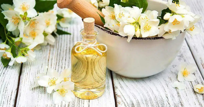 Jasmine flowers and a bottle of jasmine tea oil on a rustic white wooden table, surrounded by delicate jasmine petals, highlighting the natural beauty and fragrance of the ingredients